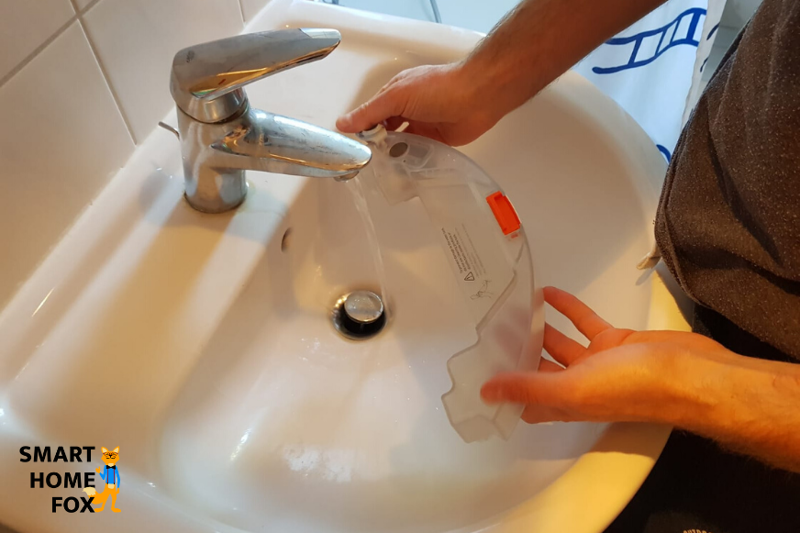 Der Wassertank eines Saugroboters mit Wischfunktion wird mit Wasser befüllt.